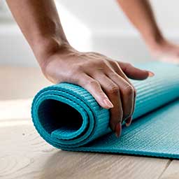 Female rolling up yoga mat on the floor