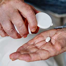 Person removing medicine from pill bottle