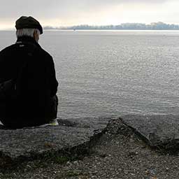 Elderly man outdoors looking out at a lake