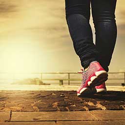 Woman wearing sneakers walking while the sun rises